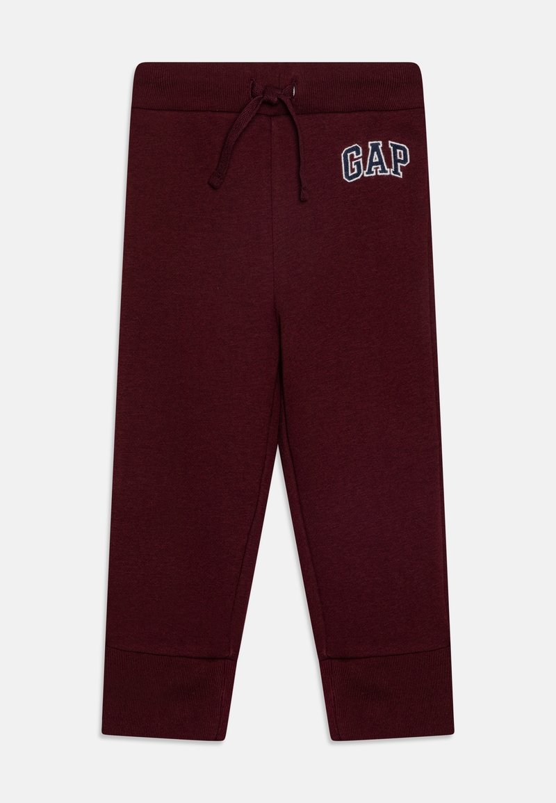 Pantalon de survêtement enfant bordeaux avec poignets côtelés, taille à cordon et logo GAP blanc en contour sur la partie supérieure de la cuisse gauche.