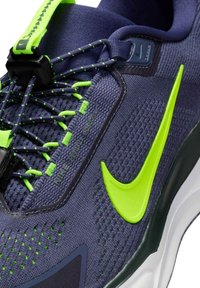 Scarpa da corsa Nike in rete blu navy con accenti verde neon. Presenta lacci elastici, corpo testurizzato e un logo prominente sul lato.