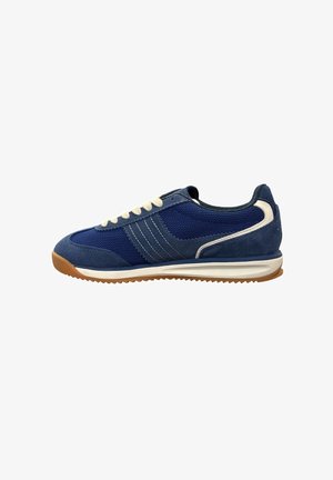 Blauwe sportsneaker met witte veters, witte en marineblauwe strepen, gestructureerde zool en bruine rubberen buitenzool, zijaanzicht op witte achtergrond.