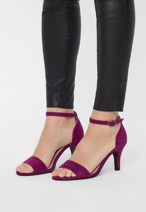 Lilla ruskind open-toe hæle med en ankelrem. Hælen er moderat høj, og skoene har en glat overflade og et minimalistisk design.