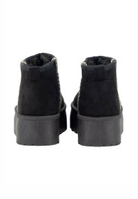 Botas de ante negro hasta el tobillo con una suela de plataforma gruesa y un reverso texturizado, que presentan costuras decorativas a lo largo del cuello.