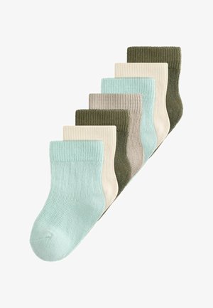 Sedem parov rebrastih pletenih nogavic srednje dolžine v pastelnem modrem, kremni, bež in olivno zeleni barvi, razporejenih v stopničasti sklad.