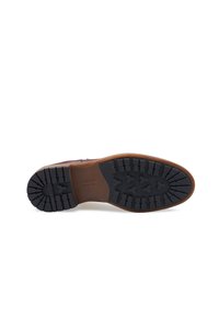 Suela de zapato de cuero en colores marrón y negro; banda de rodadura de goma texturizada para un mejor agarre; presenta patrones elevados y una forma redondeada.