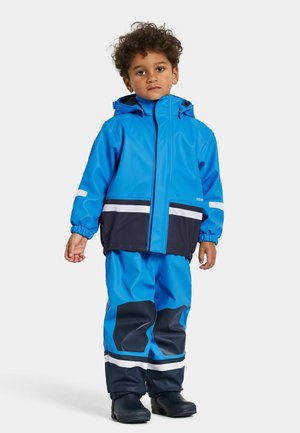 Blauwe waterdichte jas en broek met marineblauwe accenten, voorzien van elastische manchetten, reflecterende strepen en een capuchon. Vlotte, glanzende textuur.