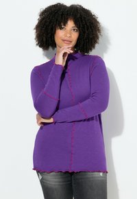 Långärmad lila topp med hög hals och kontrasterande rosa vågiga kanter, med lös passform och mjuk tygtextur.