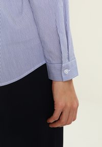 Bílá a námořnická pruhovaná košile s detaily na manžetách se zapínáním. Tkanina vypadá hladce, má přiléhavý střih a klasický design límce.