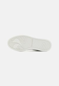 Semelle de chaussure en caoutchouc blanc présentant un motif de grip texturé, rehaussé de designs géométriques et du logo de la marque. Bords lisses avec un talon renforcé.