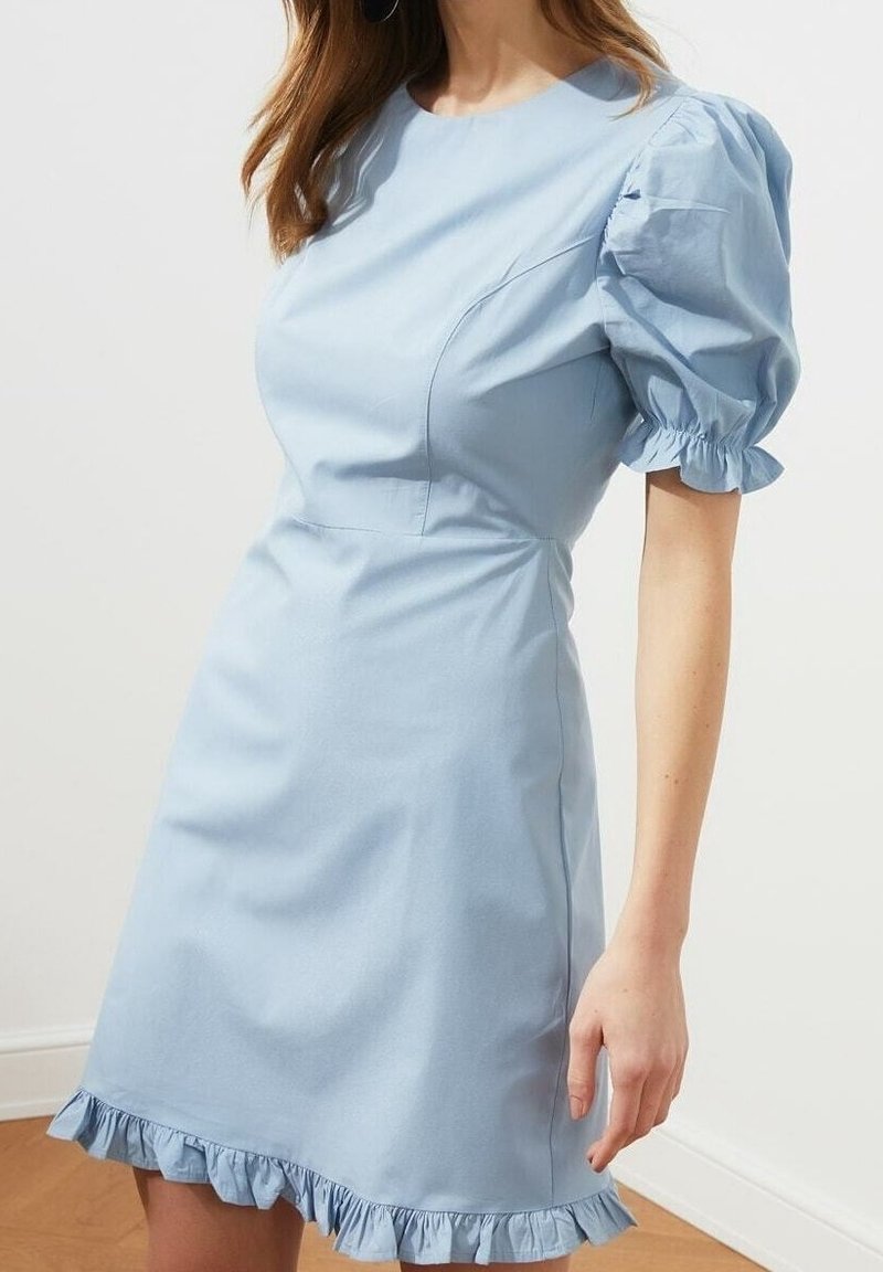 Hellblaues Kleid mit kurzen Puffärmeln, tailliertem Oberteil und gerüschtem Saum. Aus glattem Stoff gefertigt, mit dezenten Stichdetails.