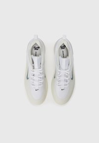 Baskets de sport blanches en maille avec une semelle en caoutchouc translucide, arborant un logo Nike gris sur le côté et un design à lacets.