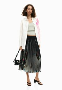 Valge nööpidega särk, hall top, must volditud seelik värviliste aktsentidega ja must käekott. Välimuse lõpetavad rihmadega kontsakingad.