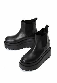 Black leather ankle boots with elastic side panels and pull tabs. Thick platform sole with a textured, ridged pattern for grip.