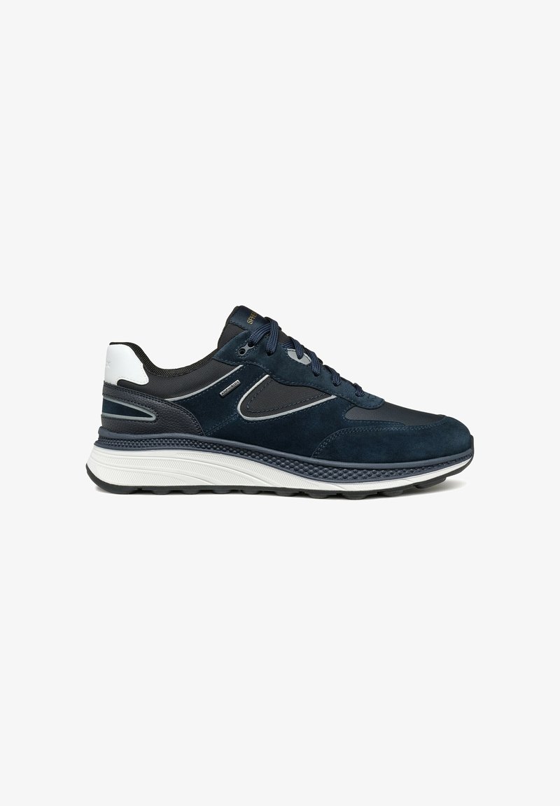 Baskets de sport en suède et mesh bleu foncé et noir avec accent blanc au talon et semelle épaisse texturée blanche et noire, vue de côté.
