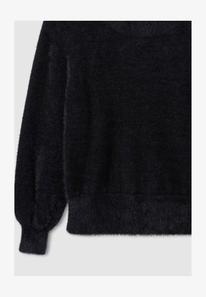 Czarny puszysty sweter z długimi balonowymi rękawami oraz prążkowanymi mankietami i dołem na jasnym tle.