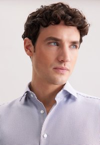 Camicia col collare con un micro-motif, caratterizzata da colori bianco e navy. Chiusura frontale con bottoni e tessuto di peso medio.