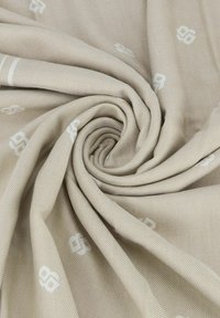Tessuto intrecciato beige con una superficie liscia, caratterizzato da sottili accenti bianchi a motivo. Il materiale appare leggero e resistente.