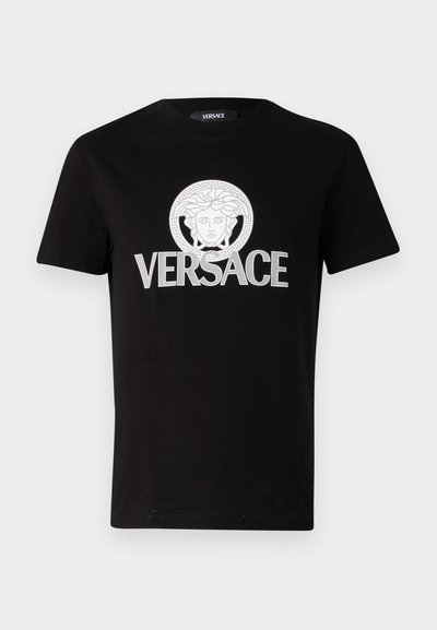 Sort bomulds T-shirt med et hvidt trykt Medusa-graphic og "VERSACE" tekst i fede bogstaver på brystet. Rund halsudskæring.