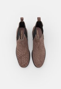 Chaussures brunes à enfiler tissées avec un dessus texturé, des panneaux élastiques sur les côtés et une languette de traction. Semelle en caoutchouc pour une meilleure adhérence et durabilité.