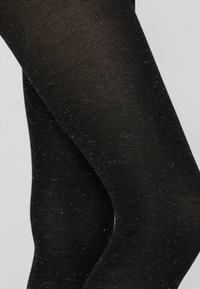 Collant neri opachi con una texture a coste, caratterizzati da sottili particelle di glitter sparse. Il design si adatta perfettamente alle gambe.