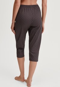 Capri-broeken in donkerbruin met een diamanten patroon in lichtroze en wit. Voorzien van een elastische tailleband en een lengte tot halverwege de kuit. Soepele textuur.