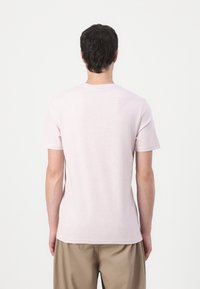 T-shirt rose à manches courtes en tissu doux et léger, avec un col rond et une coupe décontractée, vu de dos.