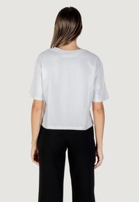 Witte cropped t-shirt met korte mouwen, ronde halslijn en een gladde katoenstructuur. Gecombineerd met zwarte broek, wat een eenvoudig en schoon ontwerp laat zien.
