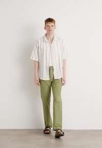White striped short-sleeve shirt, green straight-leg pants, and black sandals. Smooth fabric with light texture, casual fit, and comfortable design.
