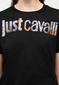 Μαύρο Τ-shirt με το κείμενο «Just Cavalli» σε μεγάλα, πολύχρωμα μοτίβα paisley και ρίγες στο στήθος.
