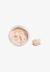 Polvere libera in un barattolo trasparente, colore beige chiaro, consistenza fine, con un po' di polvere versata accanto al barattolo. Consistenza liscia e uniforme.