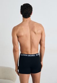 Fekete boxer alsónadrág rugalmas anyagból, fehér elasztikus derékpánttal, rajta a 'BJÖRN BORG' logóval. Egyszerű, testhezálló kialakítás.