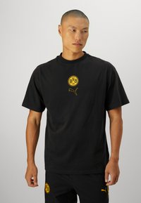 Sort bomulds T-shirt med rund halsudskæring, korte ærmer og et gult BVB-logo samt Puma emblem på brystet.