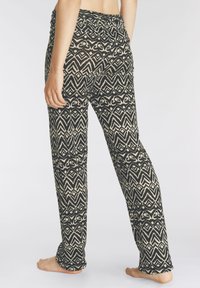 Zwarte en crèmekleurige gestreepte broek met een elastische tailleband, wijde benen en ingewikkelde geometrische ontwerpen door de hele broek.