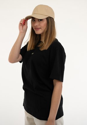 T-shirt nera in cotone con maniche corte e scollatura a girocollo, abbinata a un cappellino beige. Il cappellino presenta un design strutturato con una visiera curvata.