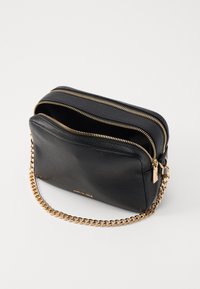 Černá kožená crossbody taška s dvěma zipovými přihrádkami, zlatě tónovaným řetízkem a texturovaným povrchem. Kompaktní obdélníkový tvar.