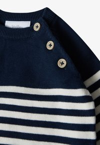 Marineblaues Strickpullover mit horizontalen weißen Streifen, rundem Halsausschnitt und dekorativen beigen Knöpfen an der Schulter. Weiche Textur.