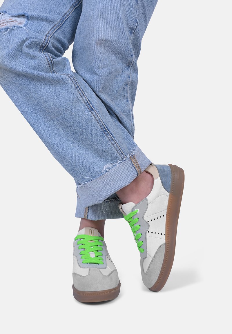 Sneaker mit einem Obermaterial aus weißem und grauem Wildleder, grünen Schnürsenkeln und einer braunen Gummisohle. Verfügt über eine runde Zehenpartie und minimale Perforationen.
