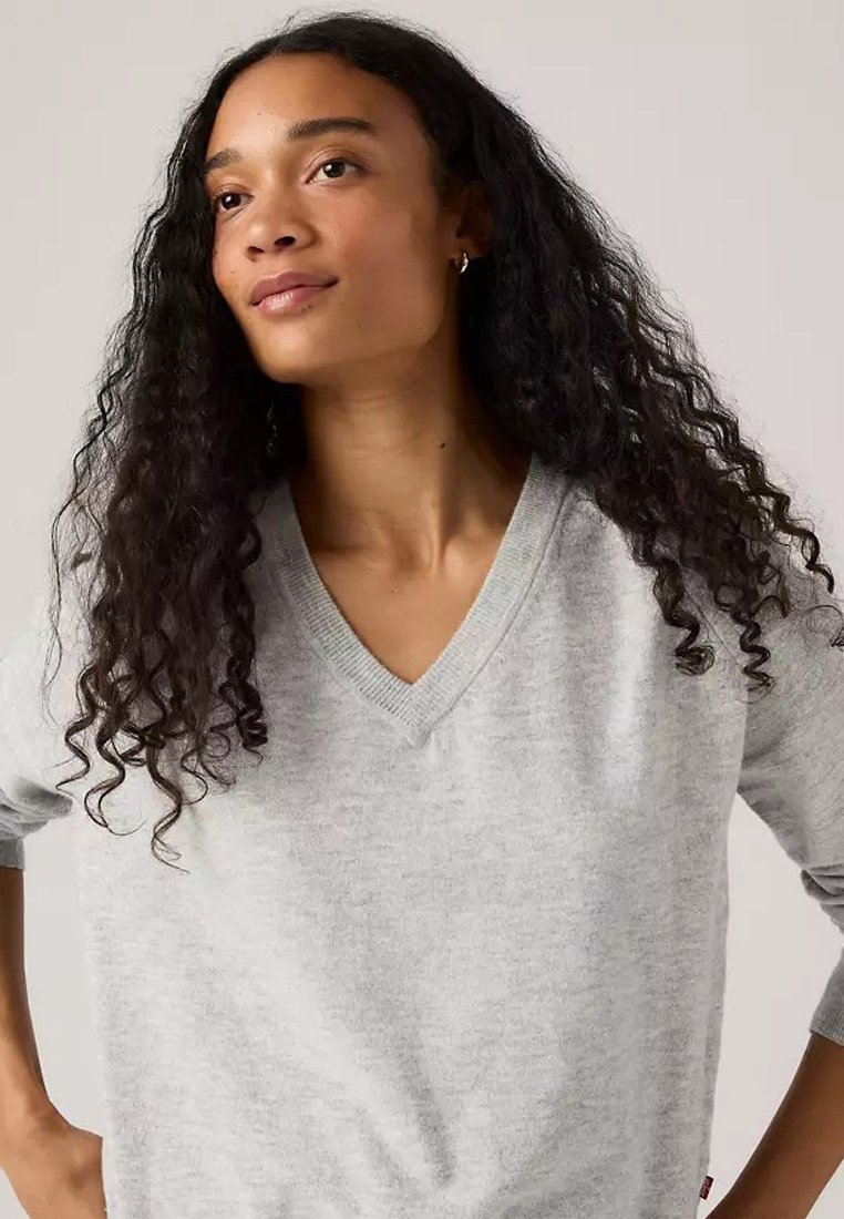 Maglione grigio chiaro a V con una texture morbida, maniche a tre quarti e colletto a coste. Etichetta notevole visibile di lato.