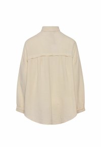 Béžová dlhá textúrovaná košeľa s vysokým golierom a detailom zozbieraného nárameníka, zobrazená zozadu na bielom pozadí.