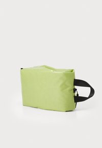 Saco retangular verde com um acabamento texturizado, apresentando uma alça preta e um fecho com zip. O design compacto torna-o versátil para vários usos.