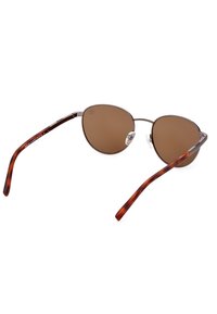Occhiali da sole con lenti color marrone, forma ovale, montatura metallica sottile e bracci con motivo tartarugato. I cuscinetti nasali regolabili offrono comfort.