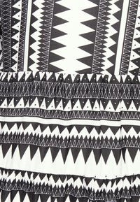 Tissu noir et blanc avec de grands motifs géométriques, y compris des triangles et des lignes. La texture est lisse avec des accents froncés.