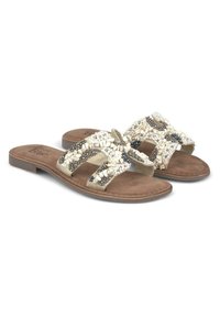 Des sandales plates présentent un dessus beige orné de perles blanches et noires, une semelle intérieure en simili-suède et une semelle en caoutchouc texturée pour une meilleure adhérence.