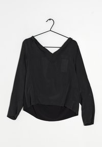 Blouse noire à manches longues avec un décolleté en V profond, dotée d'une poche sur le côté gauche, d'un ourlet arrondi et d'un tissu lisse et léger.