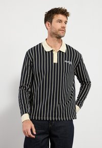 Navy longsleeve polo shirt met witte verticale strepen. Voorzien van een beige kraag en manchetten, met een klein logo op de borst.