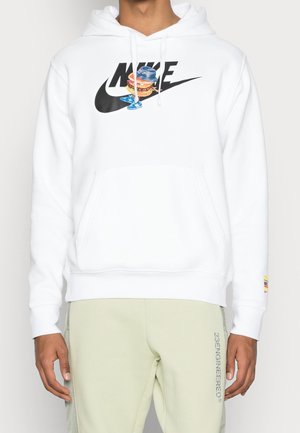 Biała bluza z kapturem z czarnym logo Nike, przedstawiająca idącego burgera w niebieskim kapeluszu i trampkach, noszona z bladoróżowymi zielonymi spodniami.