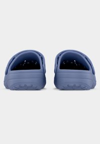 Ζευγάρι μπλε παντόφλες χωρίς κορδόνια με αεριζόμενα πάνω μέρη και ρυθμιζόμενα λουράκια στη φτέρνα, εμφανιζόμενα από πίσω σε λευκό φόντο.