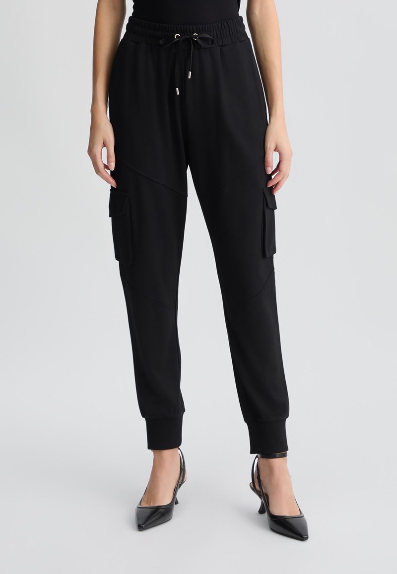 Pantaloni jogging neri realizzati in tessuto morbido con vita elastica, cordino e tasche cargo sui lati. Polsini aderenti alla caviglia.