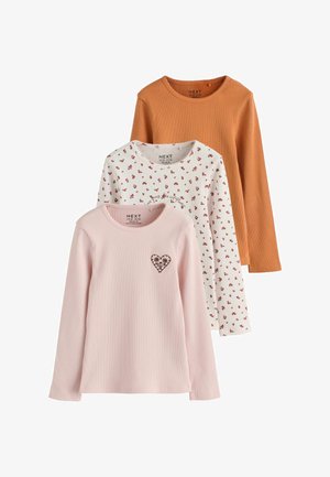 Tre ribstrikkede langærmede skjorter i pink med hjerteprint, hvid med små røde blomster og ensfarvet brændt orange, stablet vertikalt.