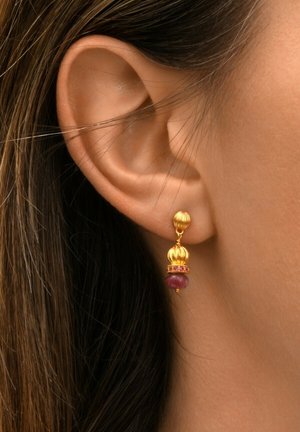 Boucles d'oreilles dorées avec un sommet sphérique, présentant une bande de petites pierres roses et une perle bordeaux en bas, suspendues à un crochet.