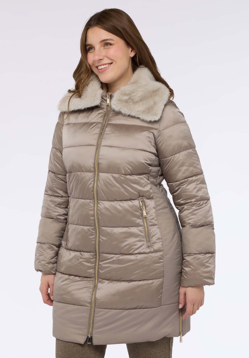 Béžový prošívaný kabát s měkkým umělým kožíškem na límci. Má zapínání na zip a boční kapsy. Hladká textura a mírně přiléhavý střih.