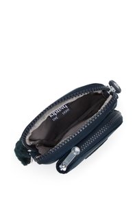 Portafoglio blu navy con zip e una texture morbida, dotato di una fodera grigia, hardware argentato e un piccolo tirazip peloso. Scomparto interno visibile.